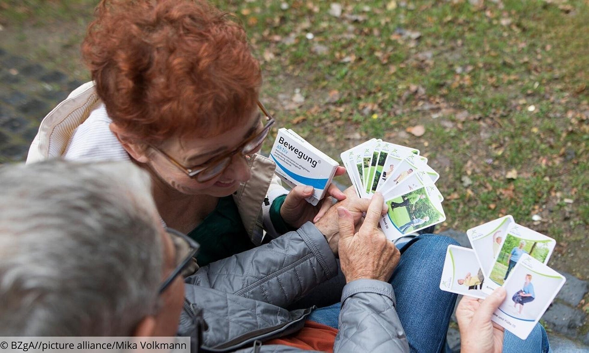 Ältere Menschen halten Übungskarten aus der Bewegungspackung