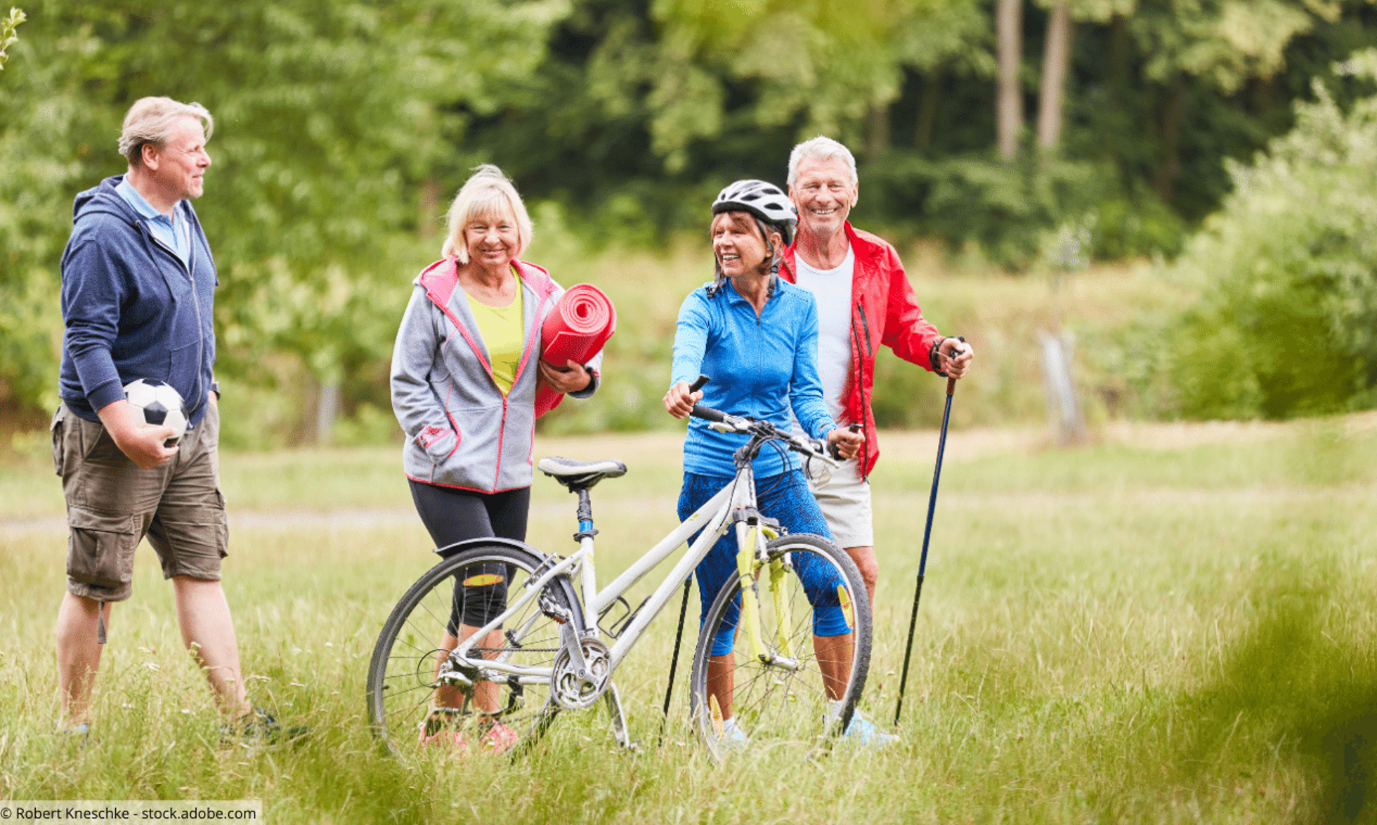 Gruppe von vier Senioren auf einer Wiese: Mann mit Fußball, Frau mit Yoga-Matte, Frau mit Fahrrad und Mann mit Nordic Walking-Stöcken