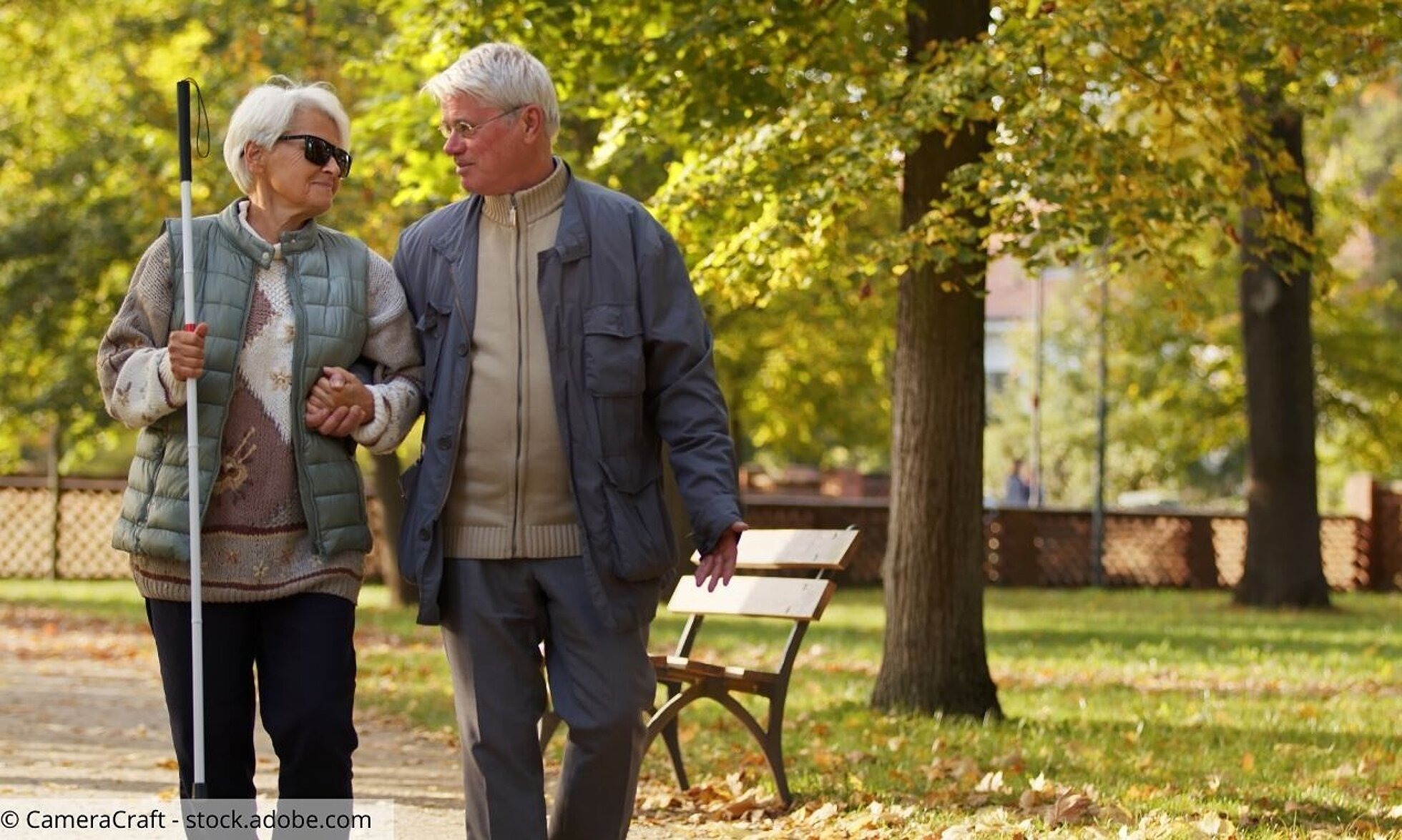 Älteres Paar im Park; Mann führt Frau mit Blindenstock