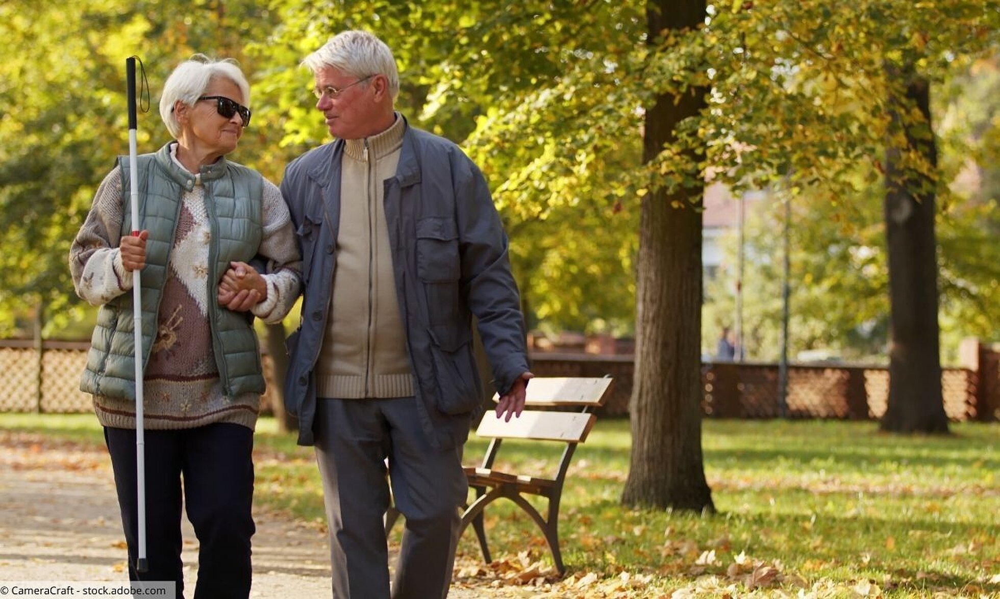 Älteres Paar im Park; Mann führt Frau mit Blindenstock