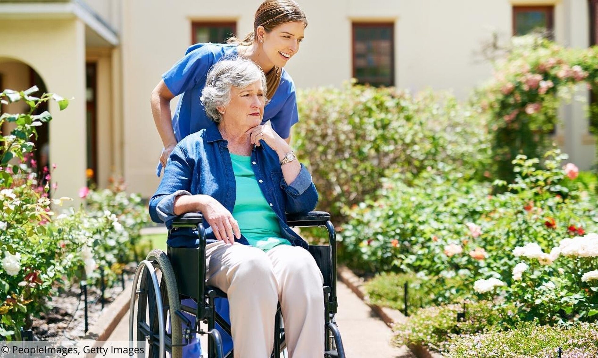 Pflegerin schiebt ältere Frau im Rollstuhl