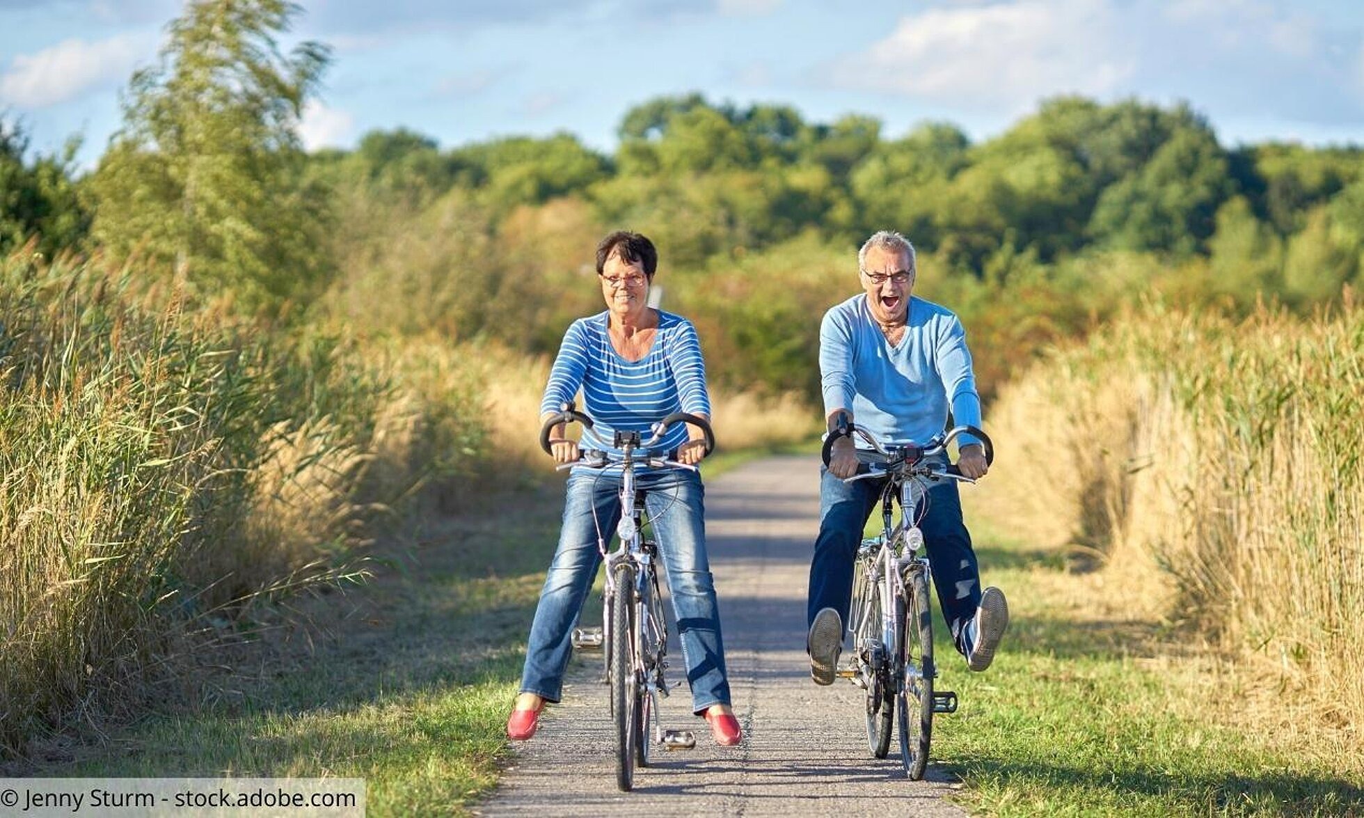 Eine ältere Frau und ein älterer Mann fahren Fahrrad auf einem Feldweg