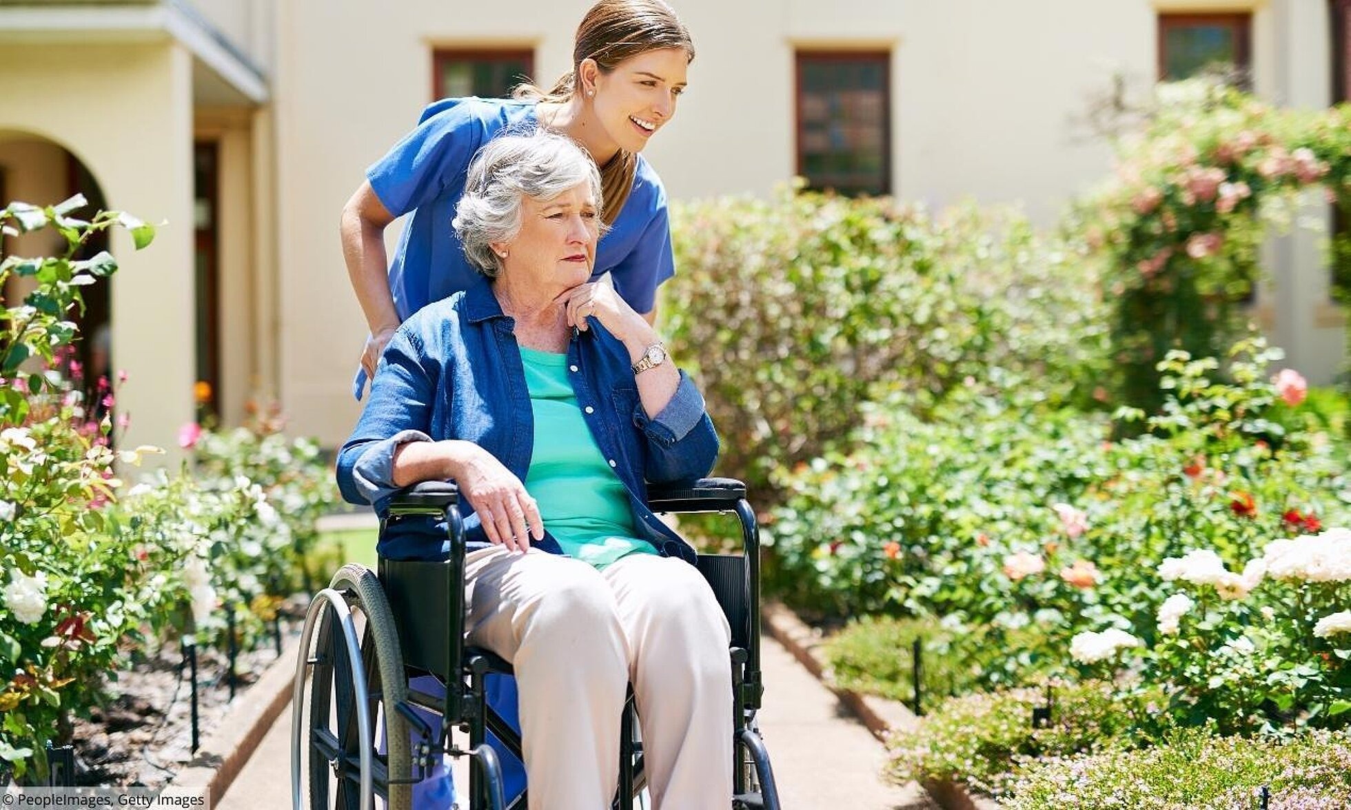 Pflegerin schiebt ältere Frau im Rollstuhl